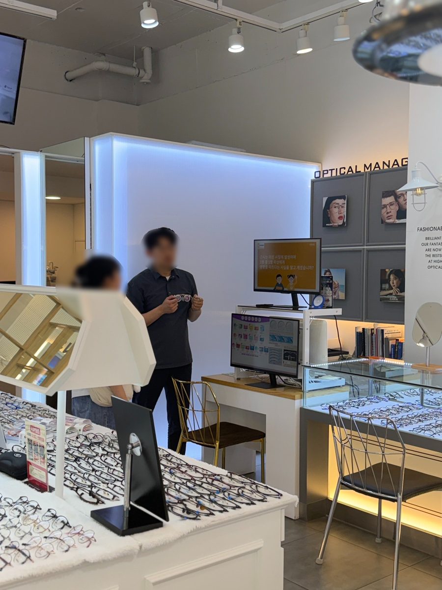 두정동 안경점 안경매니져 두정점 안경사가 고객의 안경을 살펴보며 피팅을 상담하는 모습